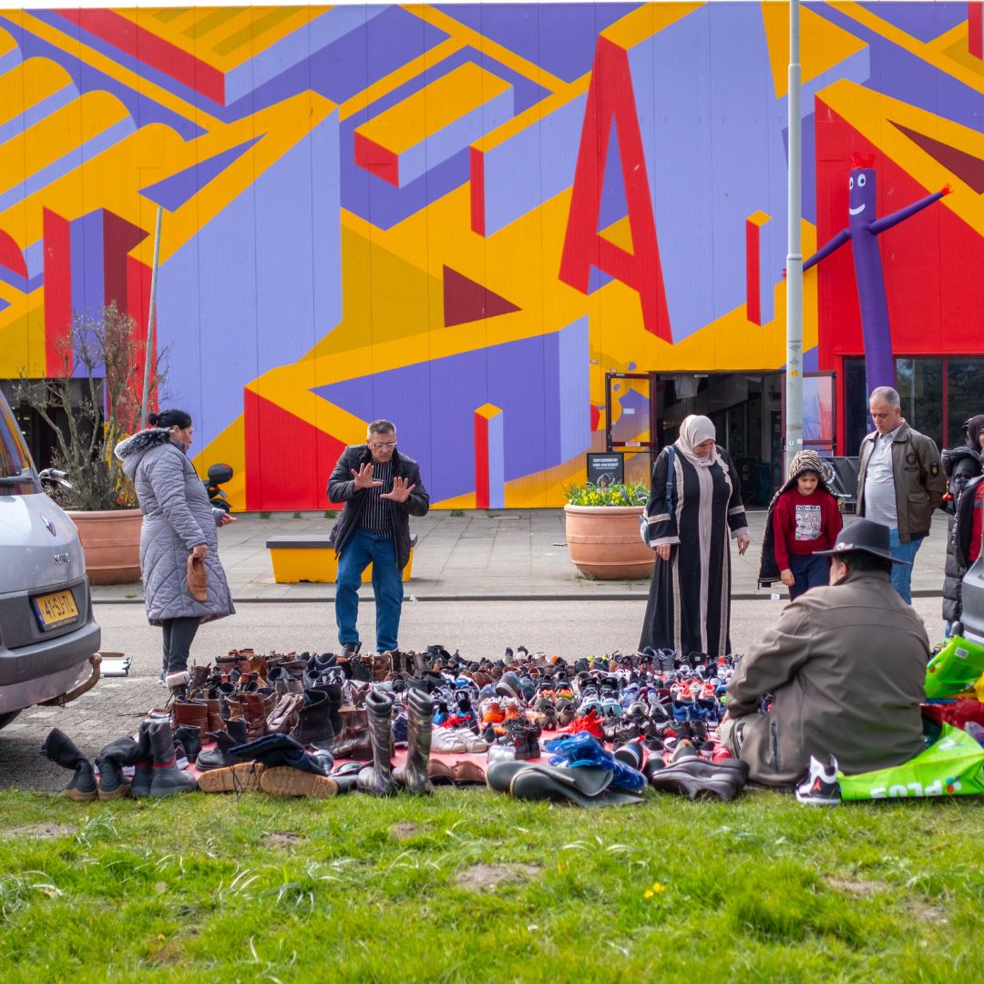 Mensen onderhandelen op de kofferbakmarkt achter Hal 30.